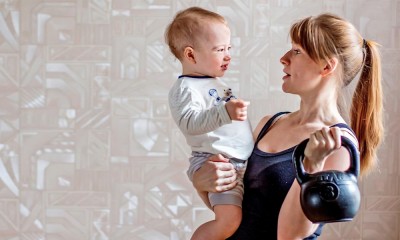 Woman holding kettle bell and child.